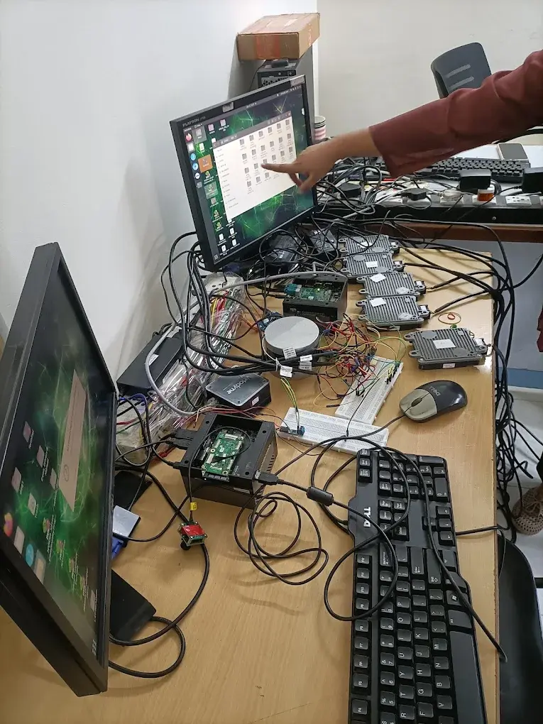 Engineer working on the Technologics Global autonomous-vehicle bench of automotive ECUs, LiDAR and single-board computers